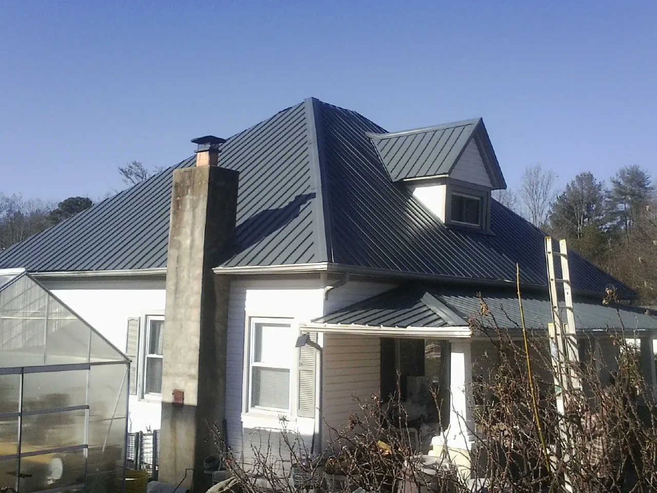 Dark blue standing seam metal roof on a white farmhouse with dormer — Slate & Tile Roof Repair by Roofing Brothers in Cedarville