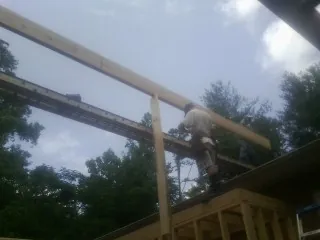 Carpenter setting a ridge beam over a new addition frame — Ice Dam Removal by Roofing Brothers in Cedarville
