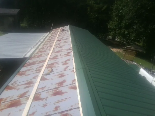Old rusted panels beside newly installed green metal roofing — Wind Damage Roof Repair by Roofing Brothers in Cedarville
