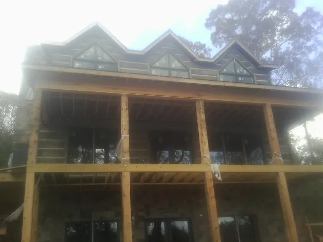 Dormers and porch framing on a large log home under construction — Roof Coating work by our crew in Cedarville