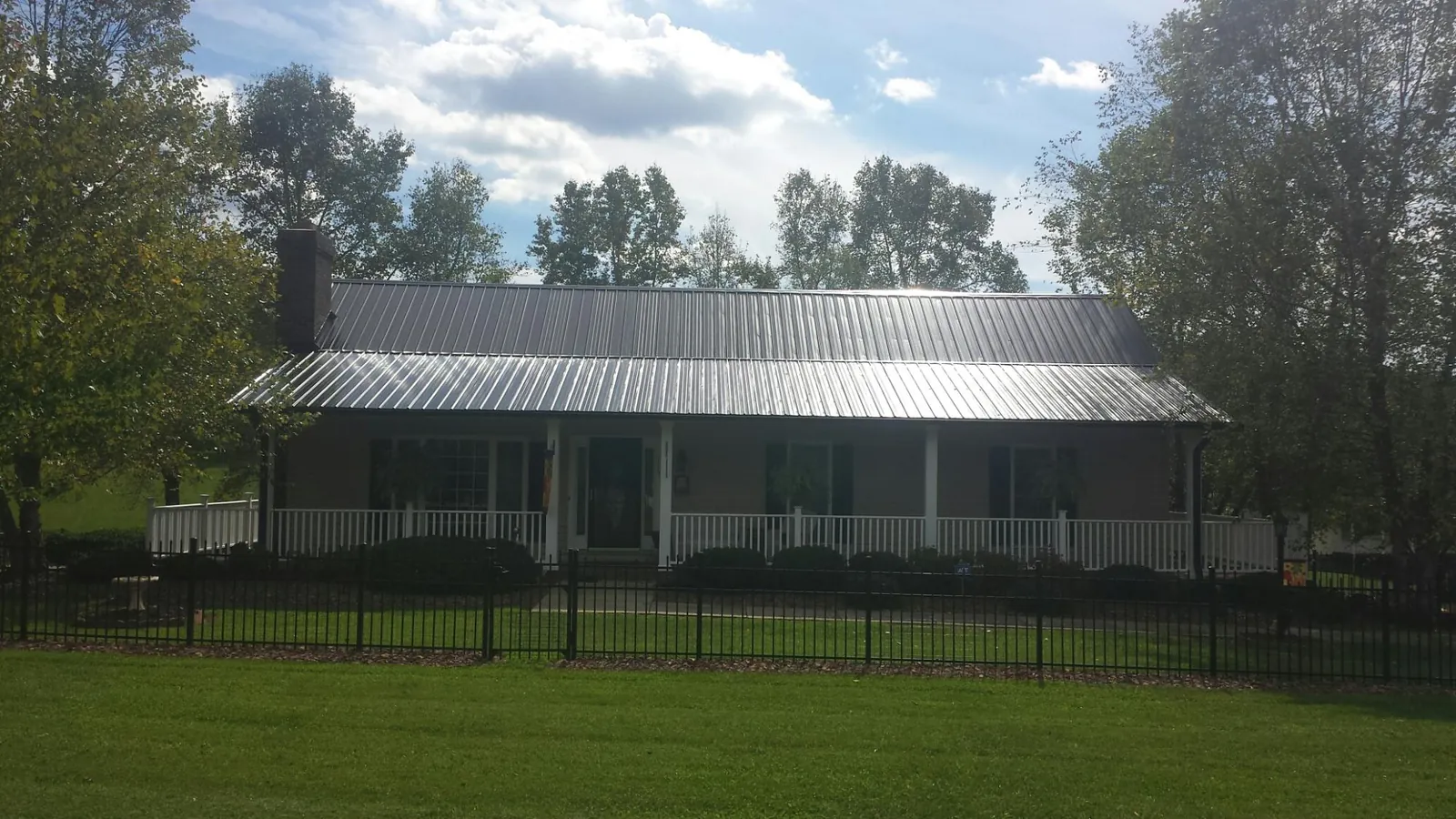 Gray metal roof on a brick ranch with a full width front porch — Gutter Guard Installation work by our crew in Cedarville