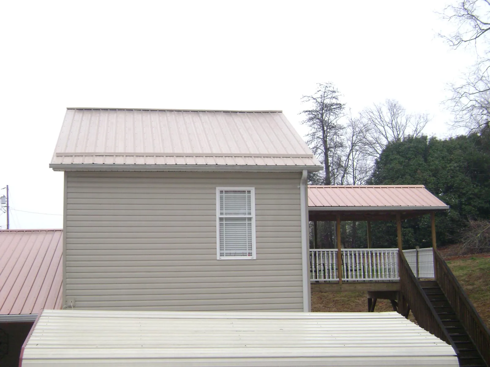 Tan metal roofs on a two story addition and attached porch, from a Roof Replacement job in Cedarville